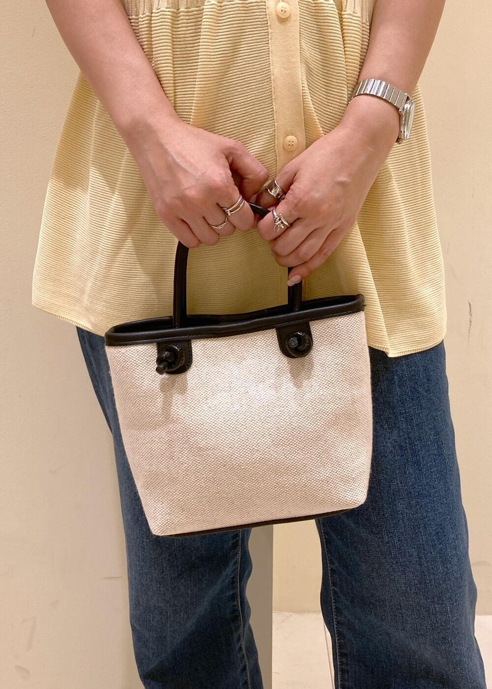 ブルー系のデニムパンツ、ブラック系のトートバッグ、ベージュ系のカーディガン/ボレロを着用したレディースの夏コーディネートの7枚目の写真