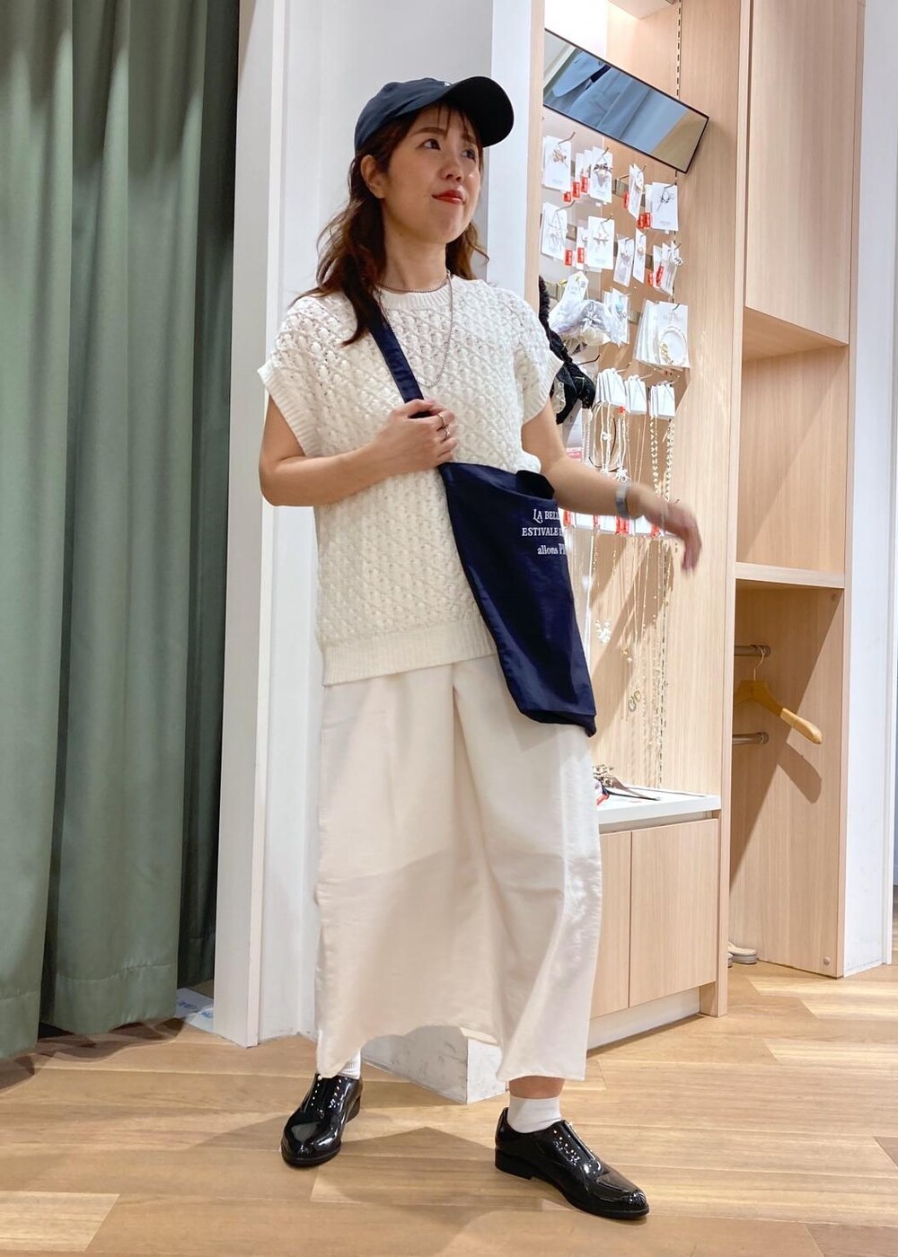 ホワイト系のワンピース、ブラック系のレインシューズ、ホワイト系のベストを着用したレディースの春コーディネートの2枚目の写真