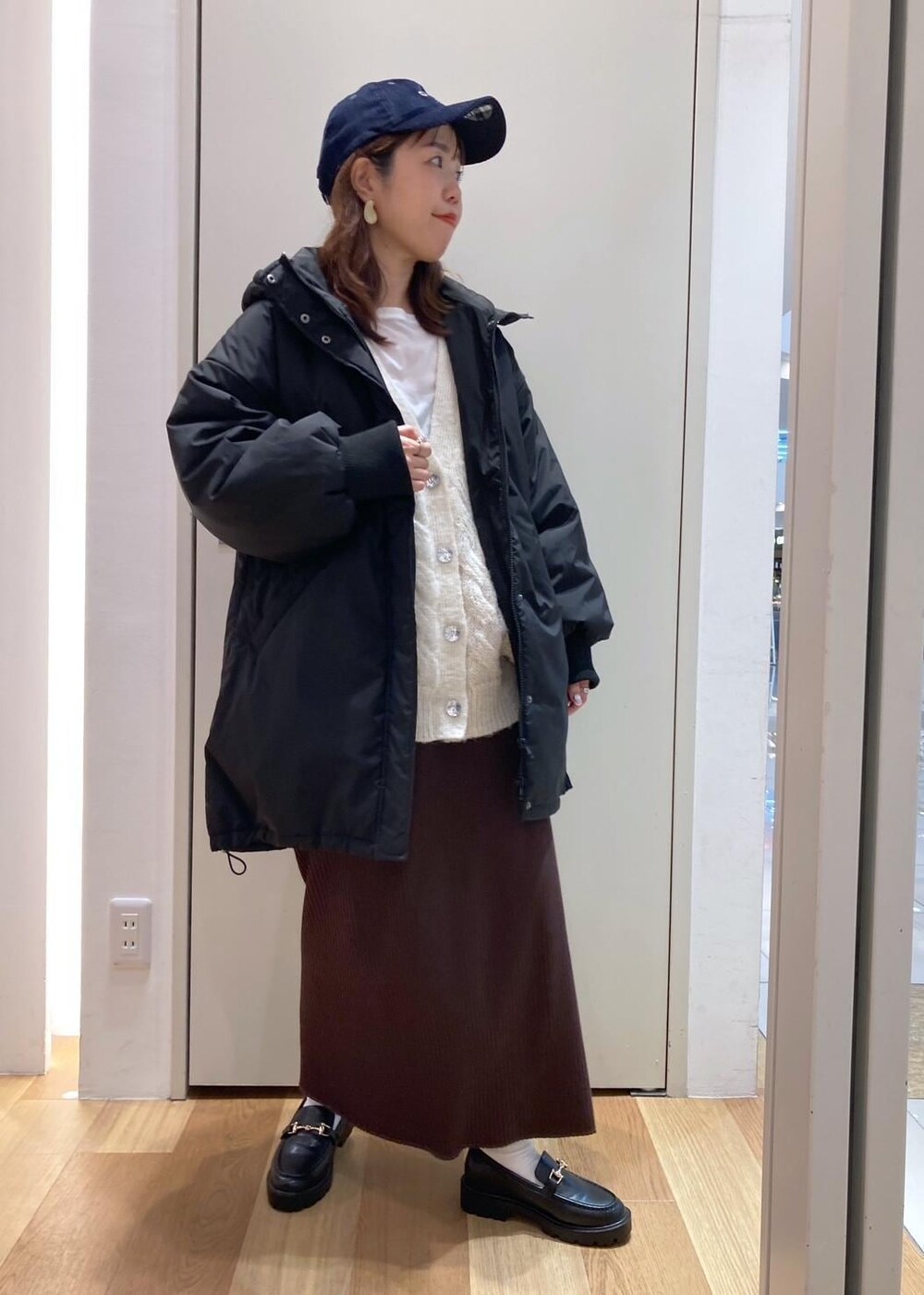 ホワイト系のTシャツ/カットソー、ブラック系のダウンジャケット/コート、ブラック系のローファーを着用したレディースの秋コーディネートの8枚目の写真