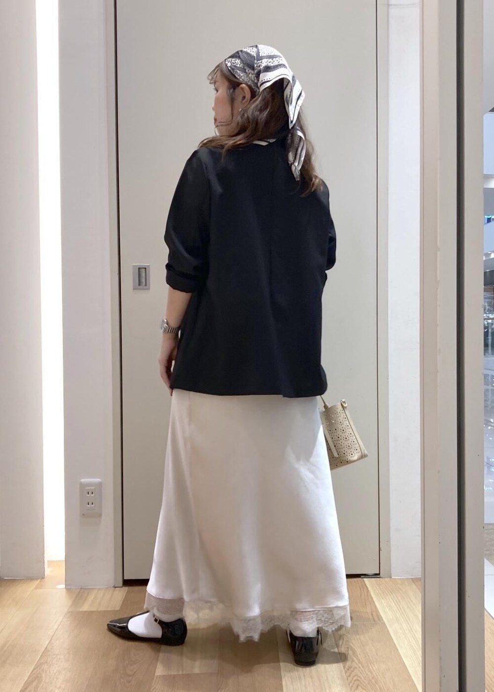 ブラック系のパンプス、ベージュ系のショルダーバッグ、ホワイト系のスカートを着用したレディースの春コーディネートの3枚目の写真