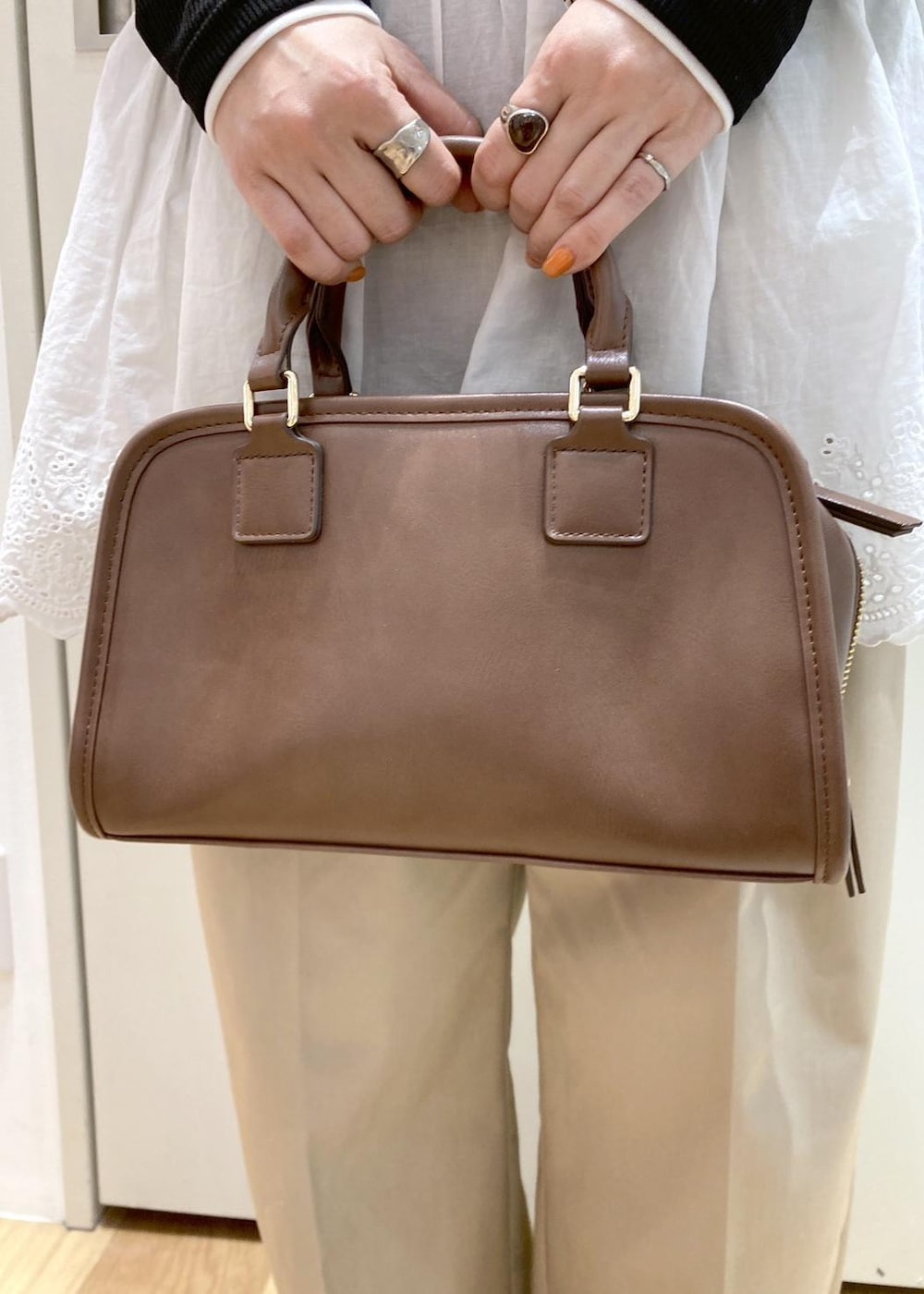 ホワイト系のキャミソール、ベージュ系のチノパンツ、ブラウン系のボストンバッグを着用したレディースの冬コーディネートの7枚目の写真