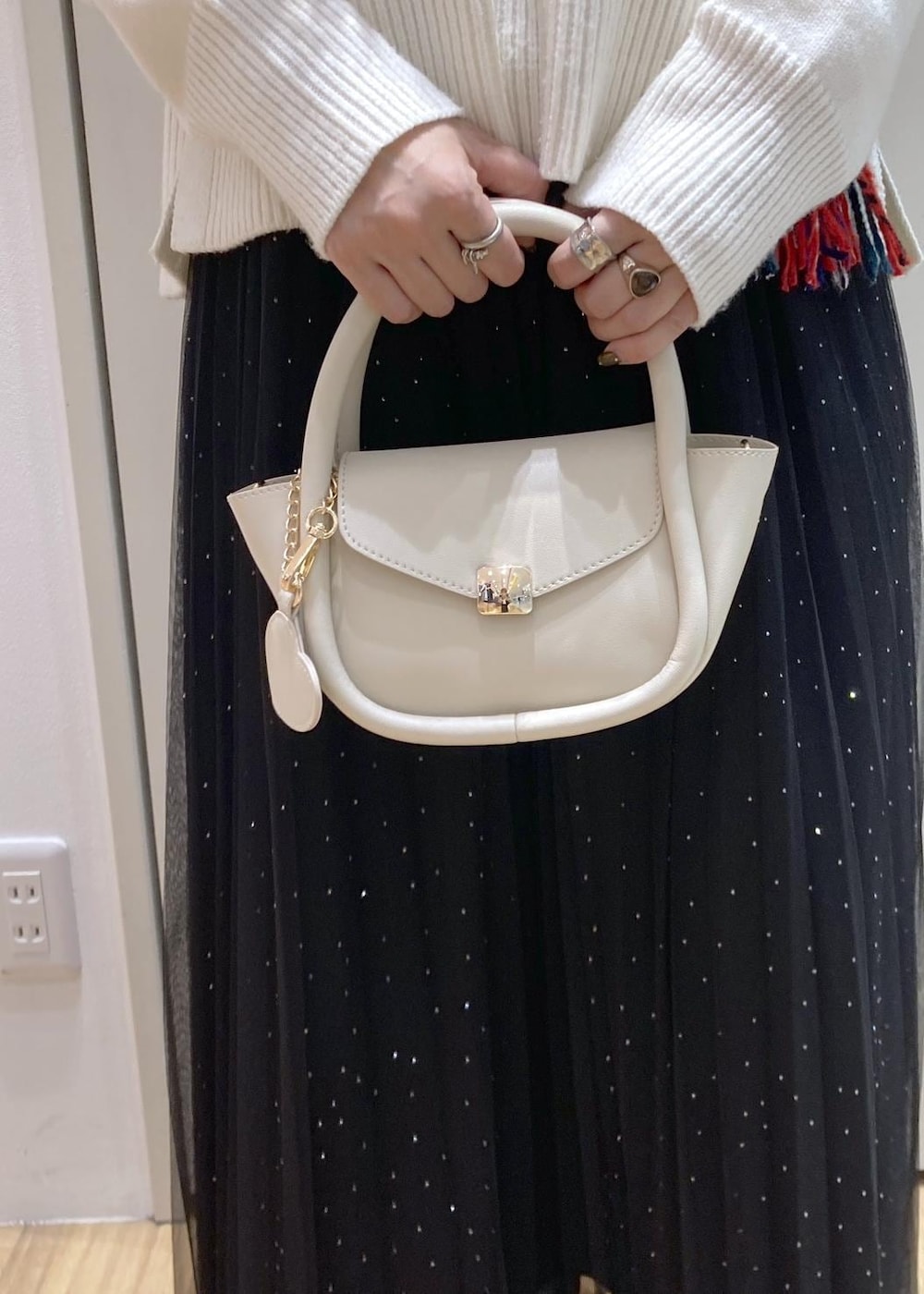 ブラック系のスカート、ホワイト系のニット/セーター、ブラック系のブーツを着用したレディースの冬コーディネートの7枚目の写真