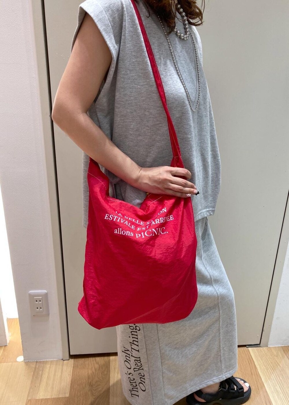 ブラック系のサンダル、レッド系のトートバッグ、グレー系のスカートを着用したレディースの夏コーディネートの7枚目の写真