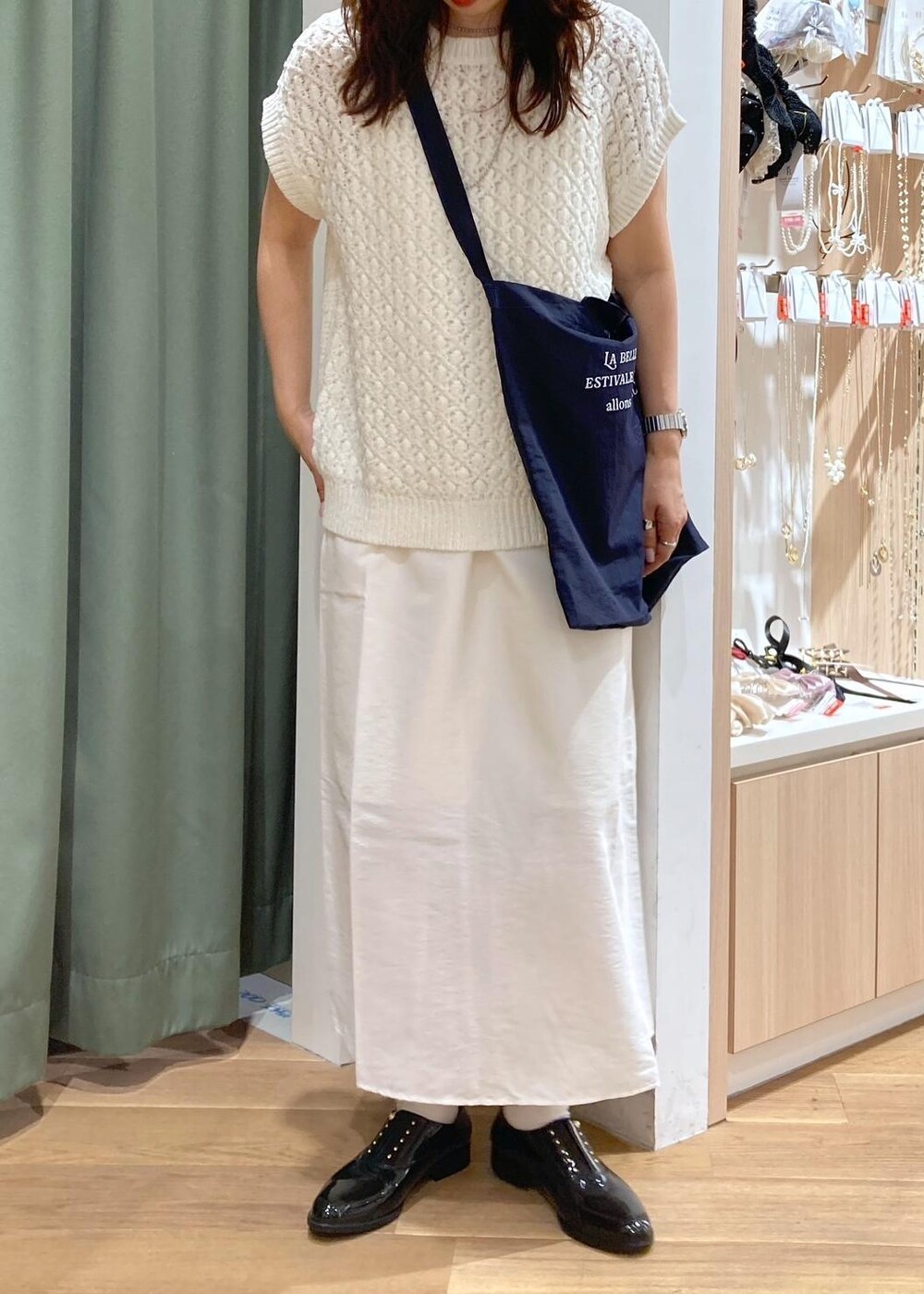 ホワイト系のワンピース、ブラック系のレインシューズ、ホワイト系のベストを着用したレディースの春コーディネートの5枚目の写真