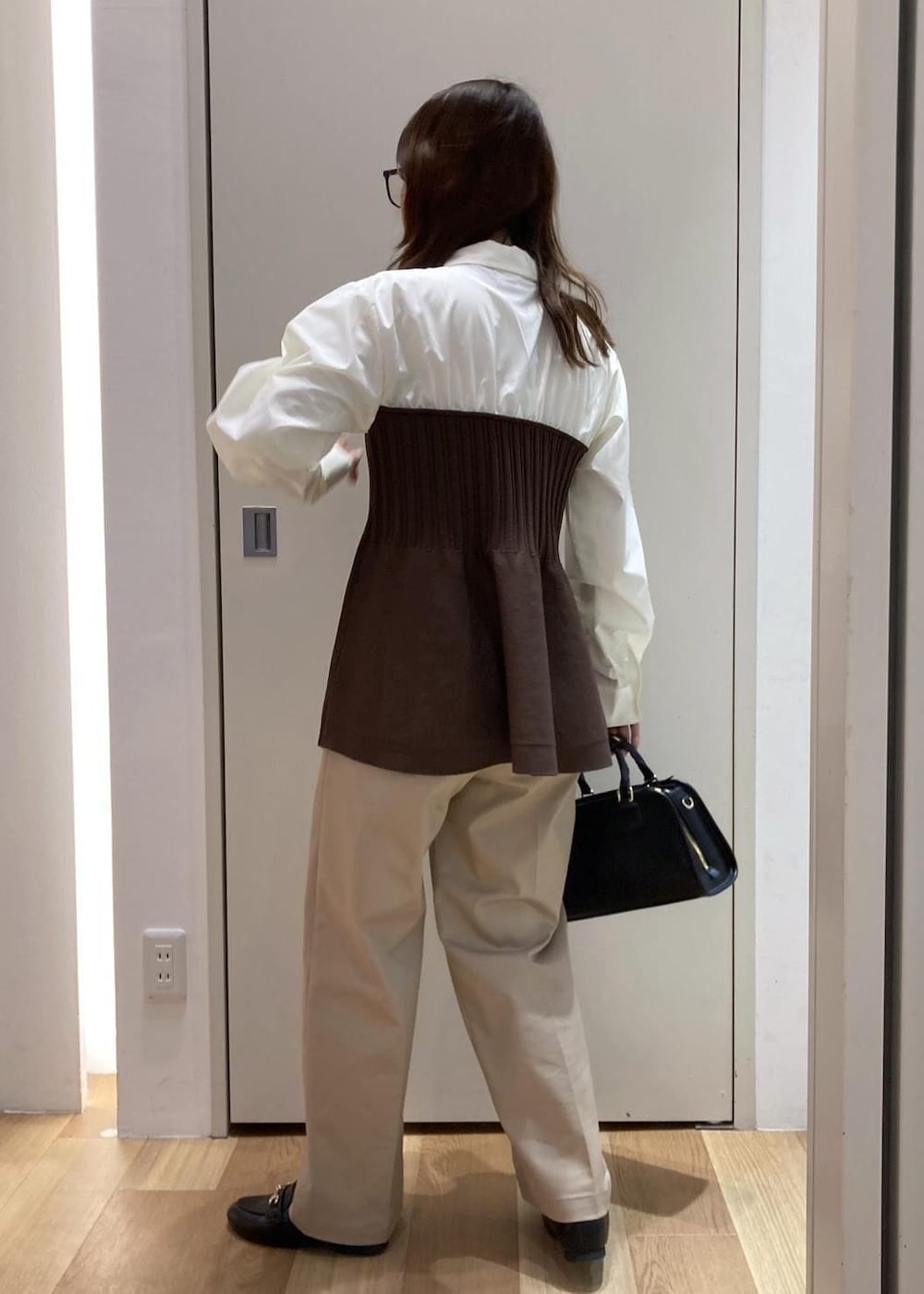 ブラック系のローファー、ブラック系のボストンバッグ、ベージュ系のチノパンツを着用したレディースの冬コーディネートの3枚目の写真