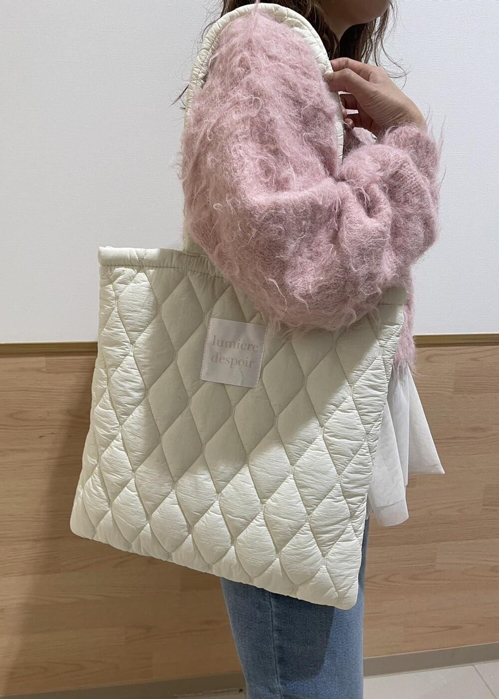 ホワイト系のブーツ、ホワイト系のトートバッグ、ブルー系のデニムパンツを着用したレディースの冬コーディネートの4枚目の写真