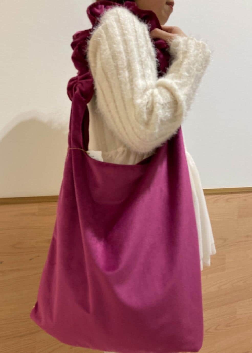 レッド系のショルダーバッグ、ホワイト系のブーツ、ホワイト系のベストを着用したレディースの冬コーディネートの5枚目の写真