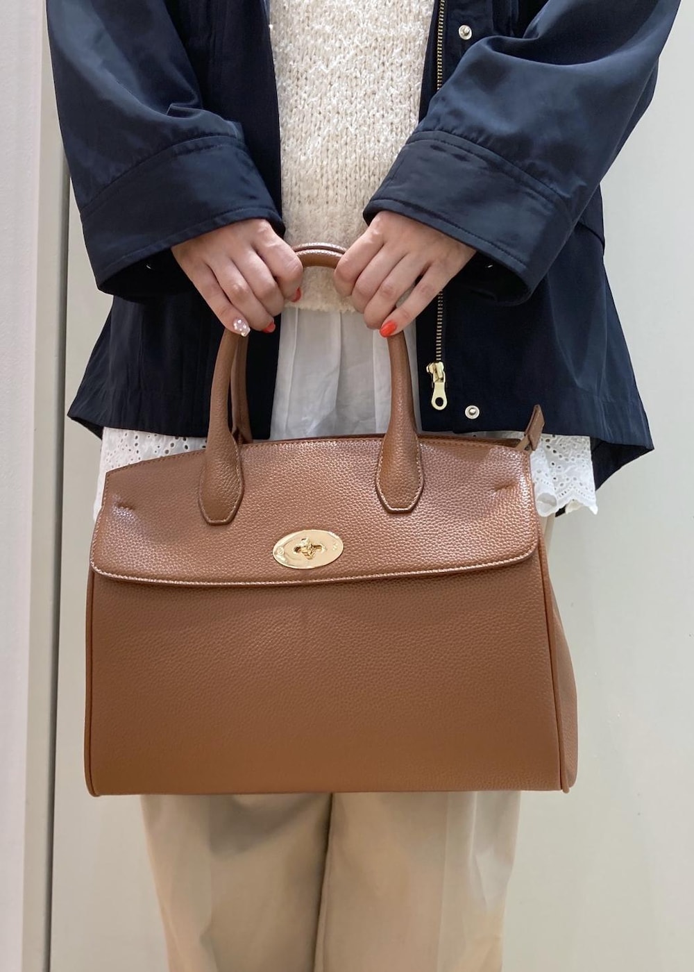 ベージュ系のチノパンツ、イエロー系のトートバッグ、ホワイト系のニット/セーターを着用したレディースの春コーディネートの9枚目の写真