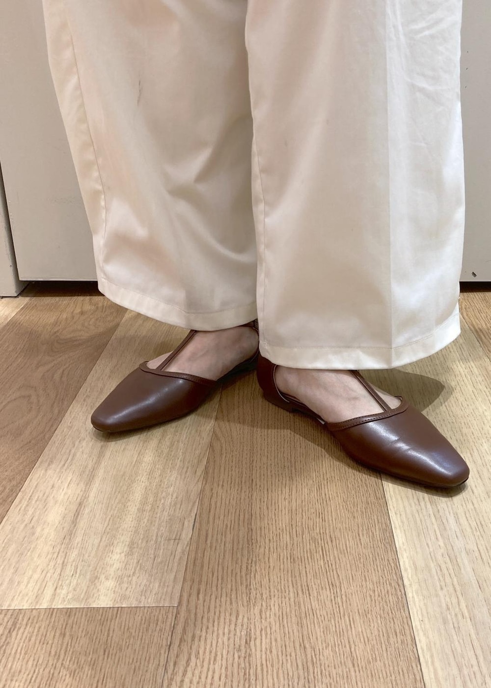 ホワイト系のトートバッグ、ブラウン系のパンプス、ホワイト系のチノパンツを着用したレディースの夏コーディネートの5枚目の写真