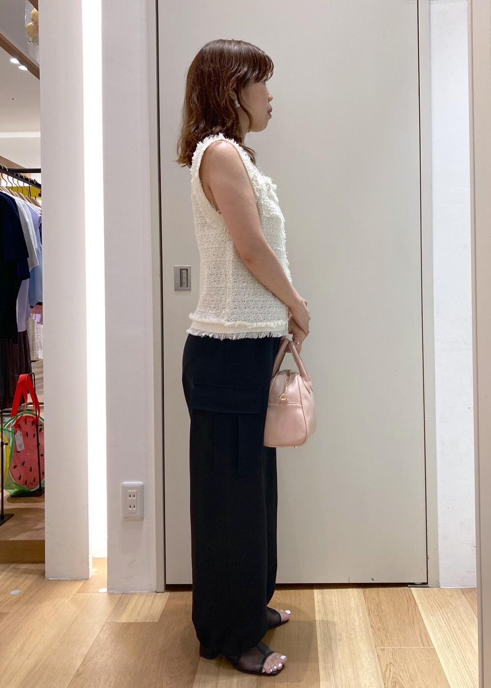 ピンク系のボストンバッグ、ブラック系のパンプス、ブラック系のカーゴパンツを着用したレディースの夏コーディネートの3枚目の写真