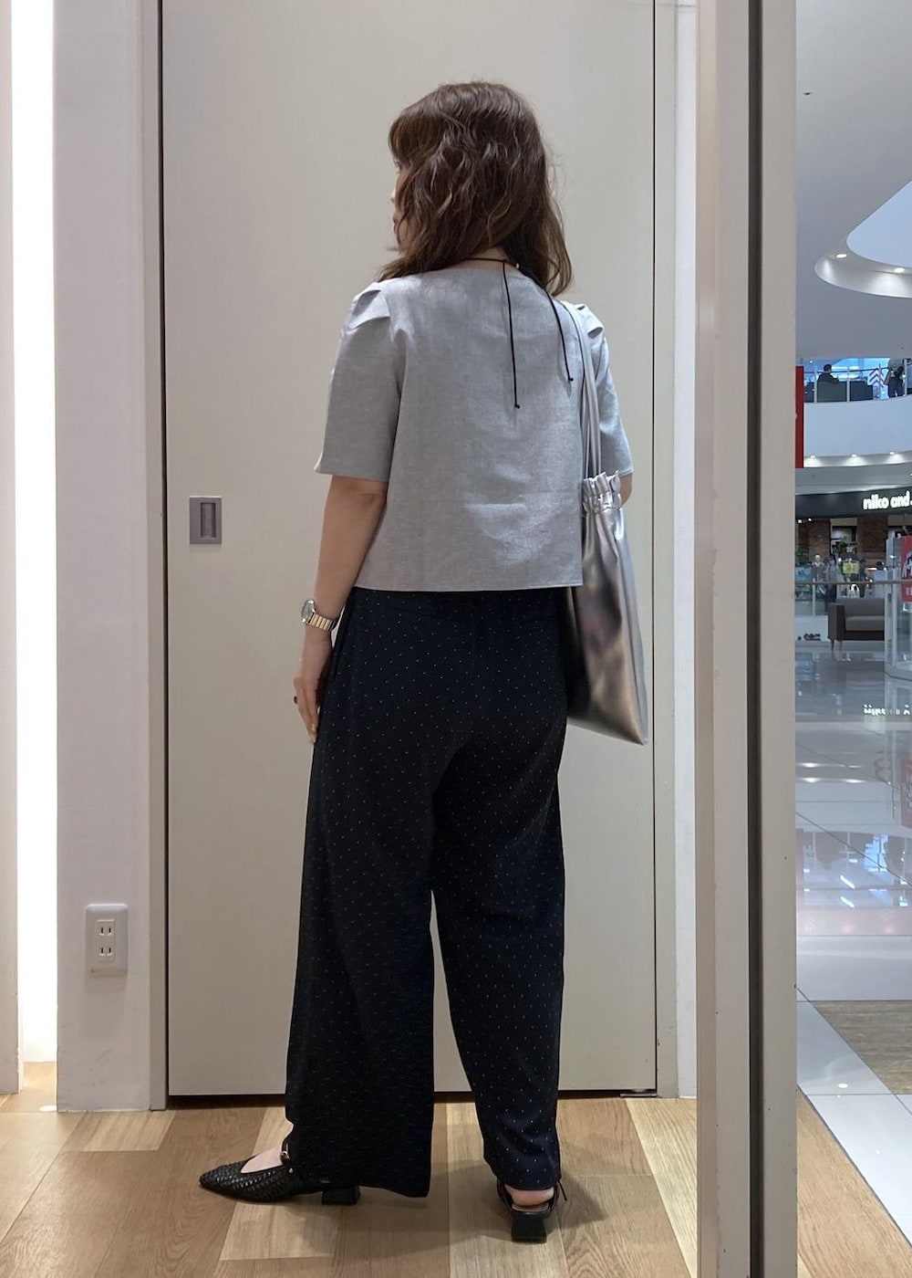 ブラック系のパンプス、シルバー系のトートバッグ、グレー系のシャツ/ブラウスを着用したレディースの夏コーディネートの3枚目の写真
