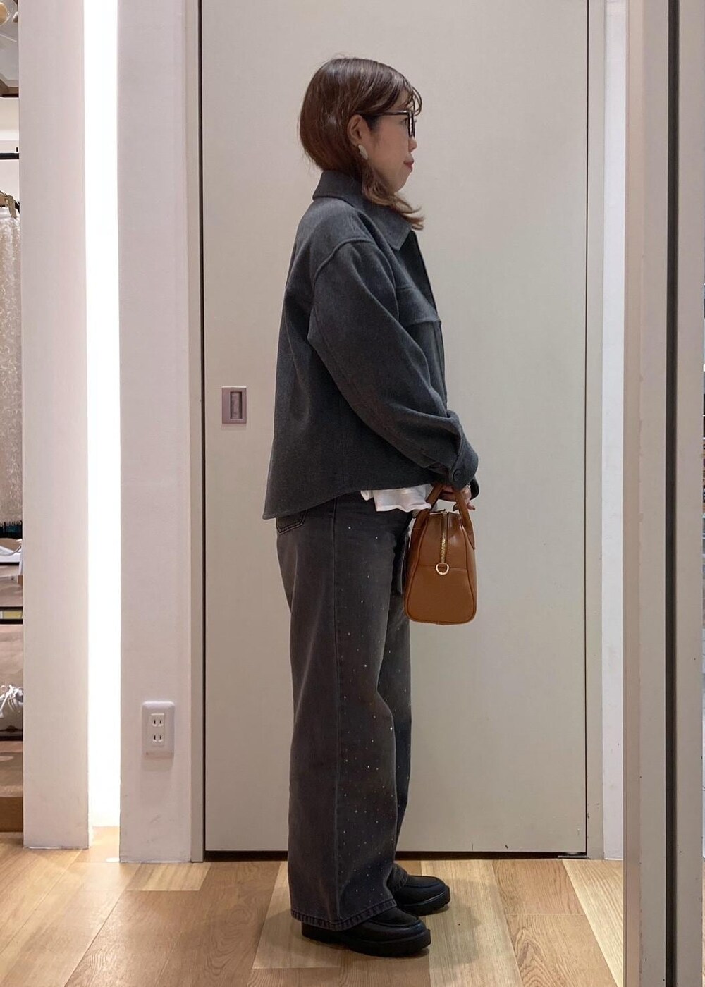 グレー系のブルゾン、グレー系のニット/セーター、ホワイト系のTシャツ/カットソーを着用したレディースの秋コーディネートの2枚目の写真