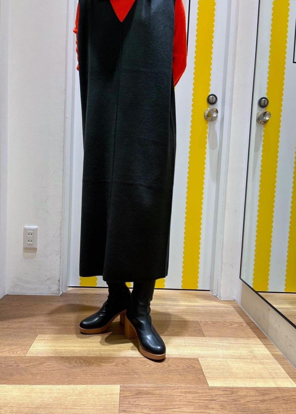 グレー系のジャンパースカート、レッド系のニット/セーター、ブラック系のブーツを着用したレディースの冬コーディネートの5枚目の写真