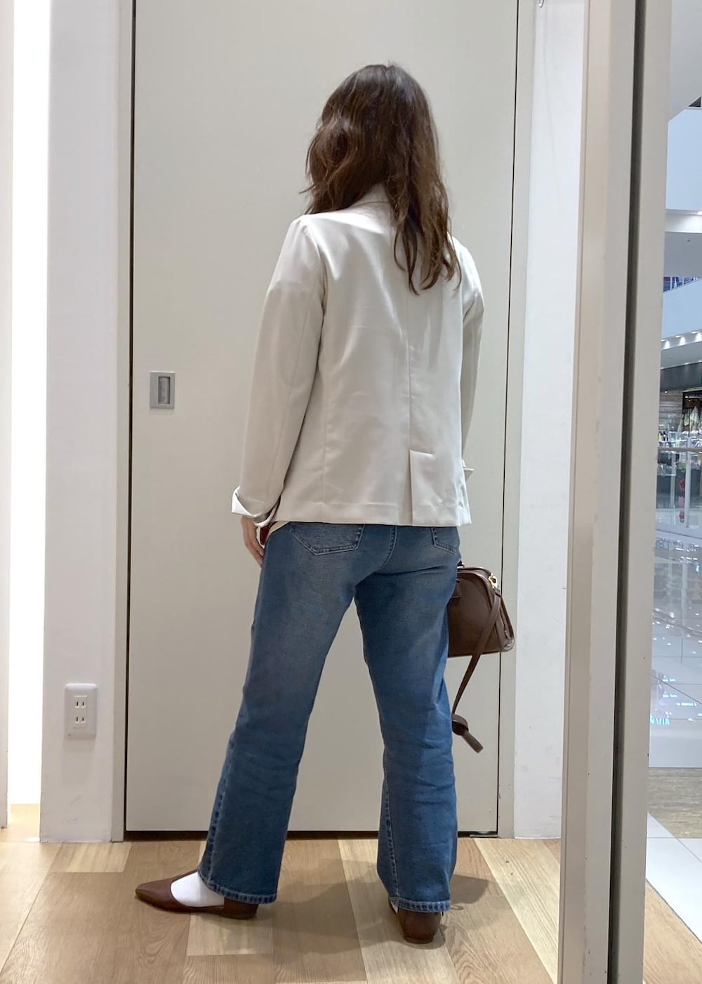 ブラウン系のボストンバッグ、ブルー系のデニムパンツ、ブラウン系のパンプスを着用したレディースの春コーディネートの3枚目の写真