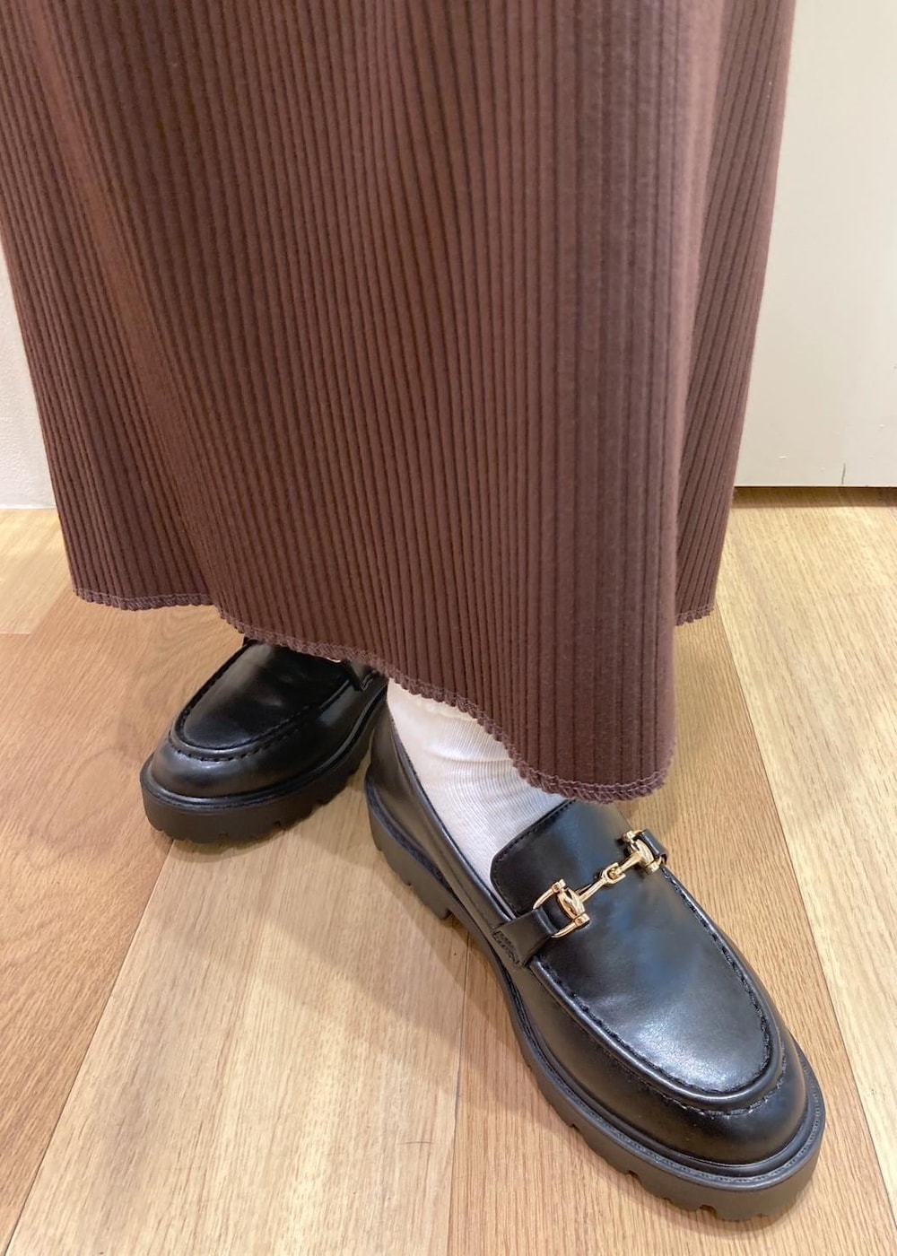 ホワイト系のTシャツ/カットソー、ブラック系のダウンジャケット/コート、ブラック系のローファーを着用したレディースの秋コーディネートの6枚目の写真