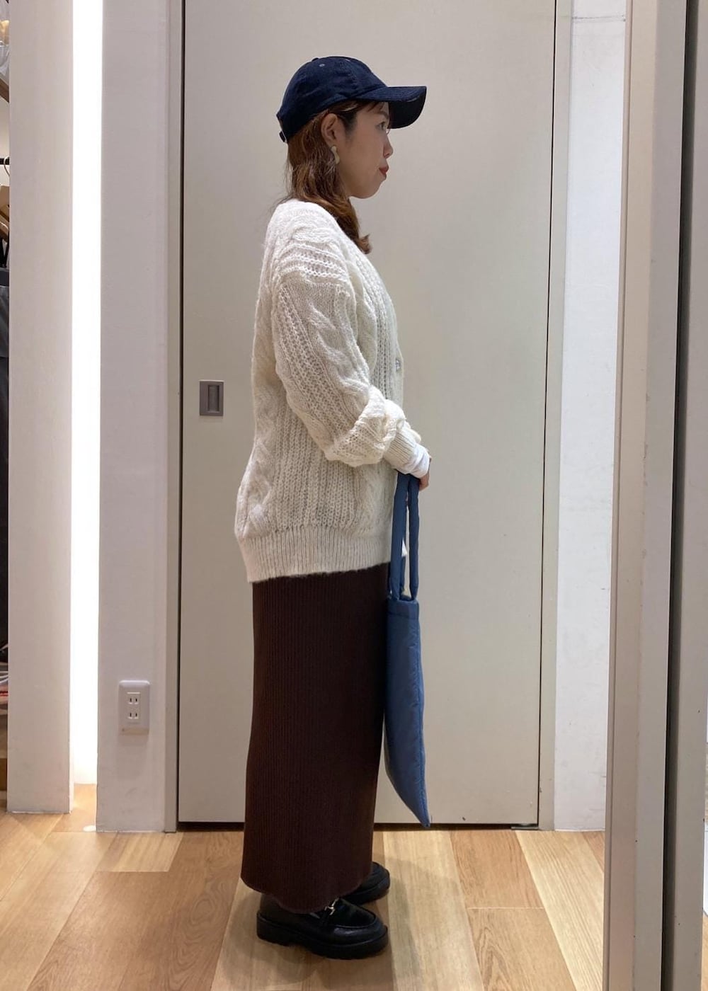 ホワイト系のTシャツ/カットソー、ブラック系のダウンジャケット/コート、ブラック系のローファーを着用したレディースの秋コーディネートの2枚目の写真