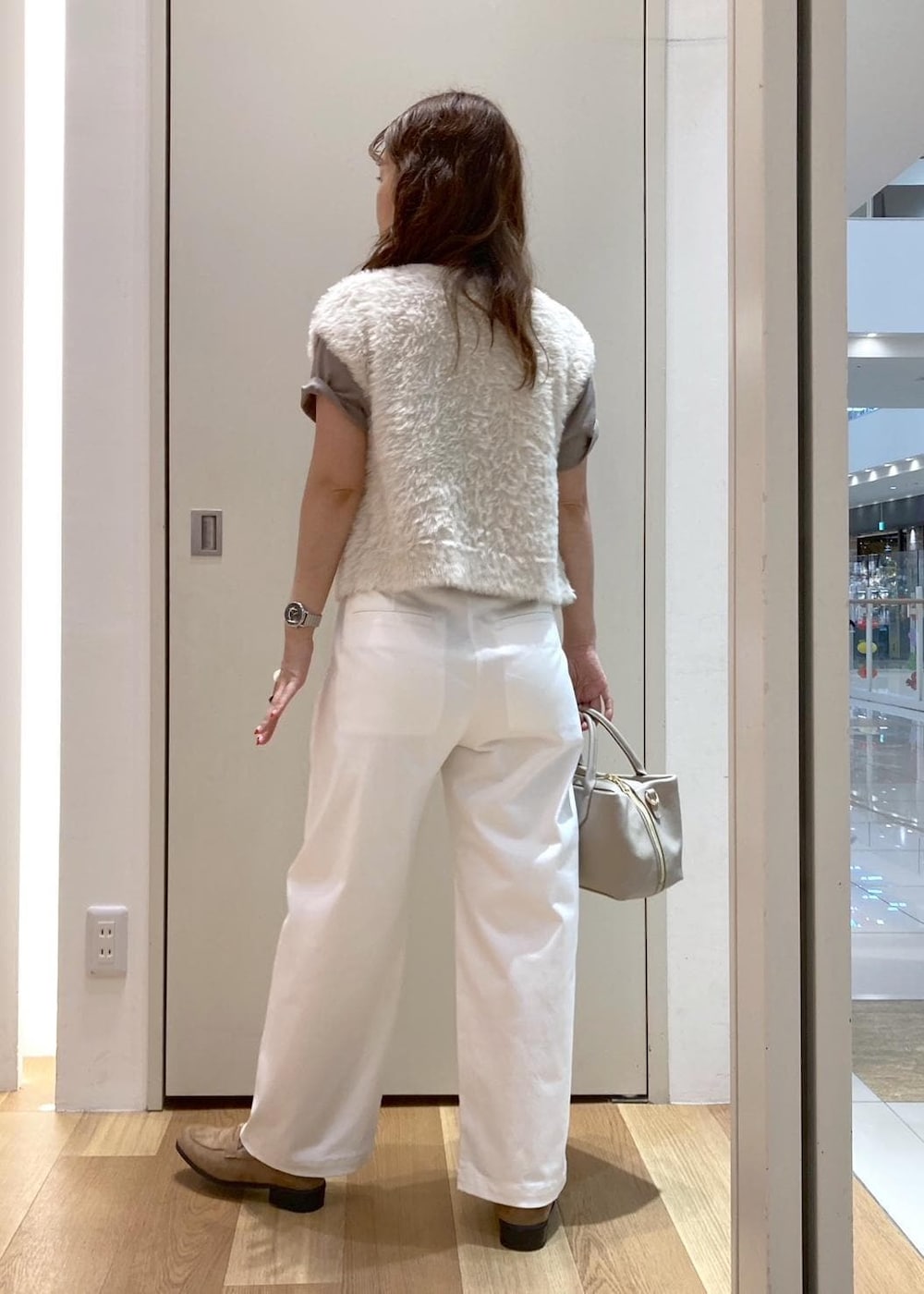 ベージュ系のトートバッグ、グリーン系のTシャツ/カットソー、ホワイト系のベストを着用したレディースの夏コーディネートの3枚目の写真