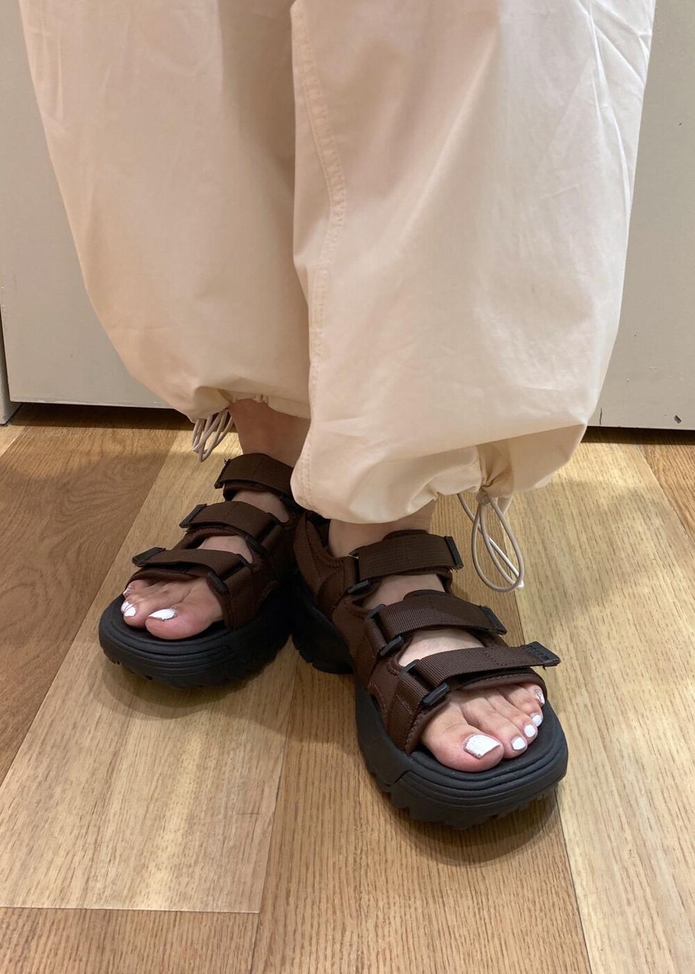 ブラウン系のトートバッグ、ブラウン系のサンダル、ホワイト系のシャツ/ブラウスを着用したレディースの夏コーディネートの8枚目の写真