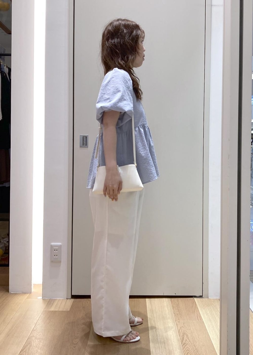 ホワイト系のショルダーバッグ、ブルー系のシャツ/ブラウス、ホワイト系のサンダルを着用したレディースの夏コーディネートの2枚目の写真