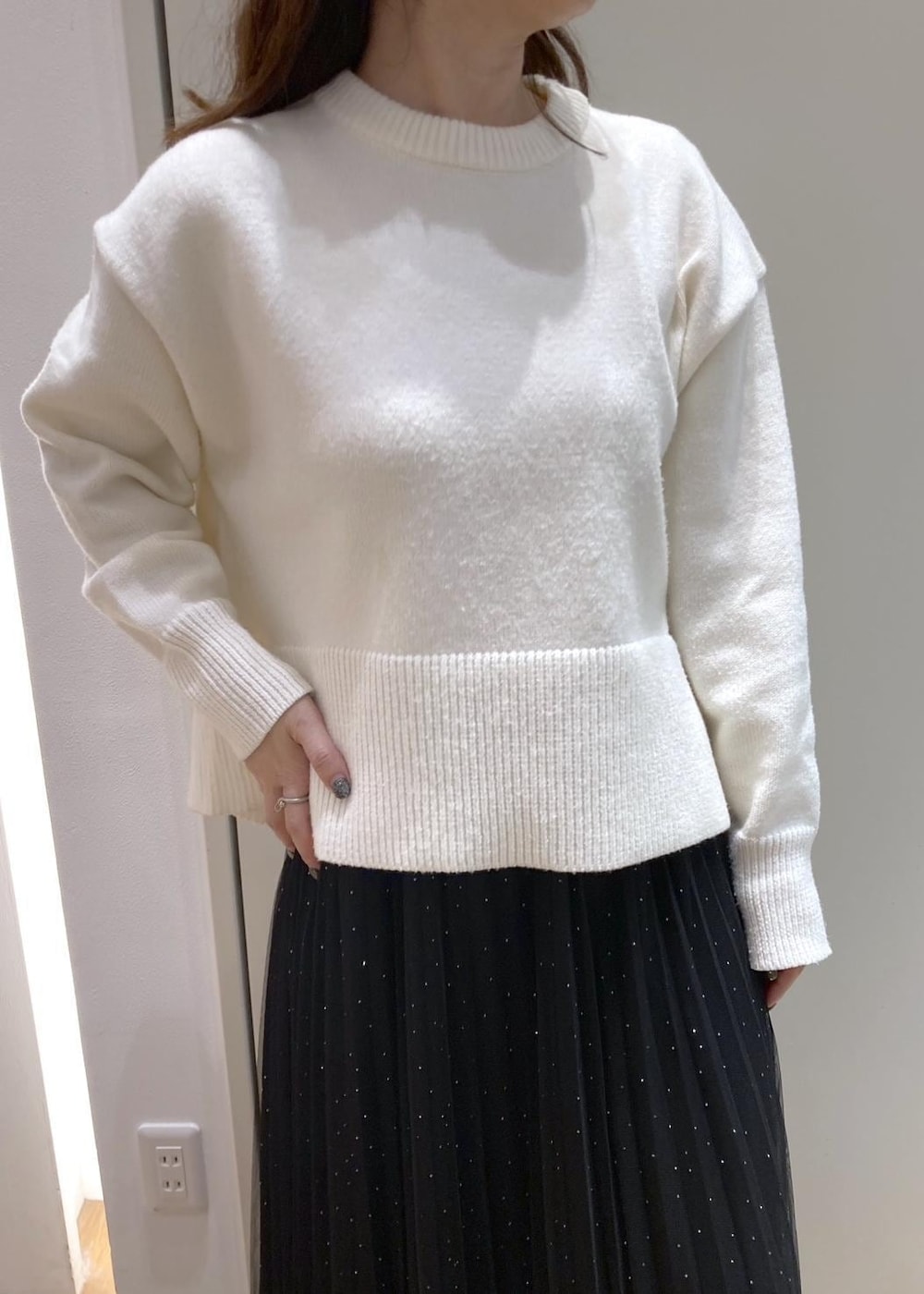 ブラック系のスカート、ホワイト系のニット/セーター、ブラック系のブーツを着用したレディースの冬コーディネートの5枚目の写真