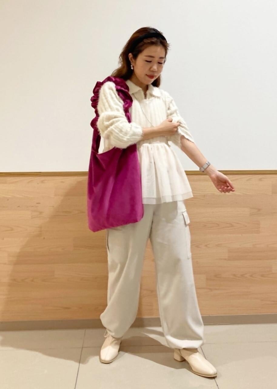 レッド系のショルダーバッグ、ホワイト系のブーツ、ホワイト系のベストを着用したレディースの冬コーディネートの2枚目の写真