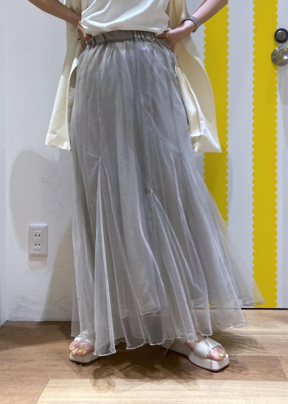 ホワイト系のサンダル、ベージュ系のショルダーバッグ、ホワイト系のベストを着用したレディースの春コーディネートの4枚目の写真