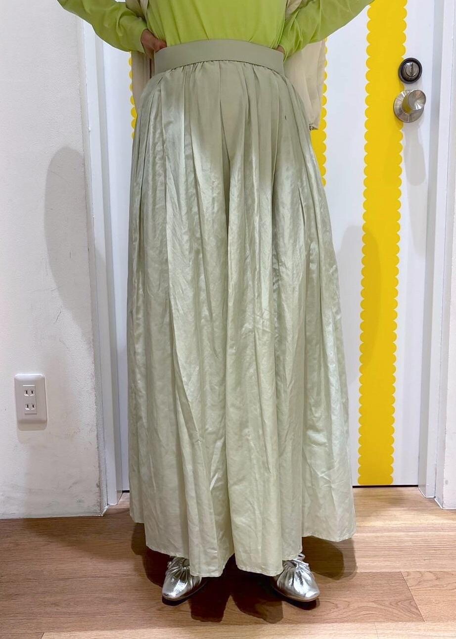 グリーン系のスカート、シルバー系のパンプス、ホワイト系のベストを着用したレディースの春コーディネートの3枚目の写真