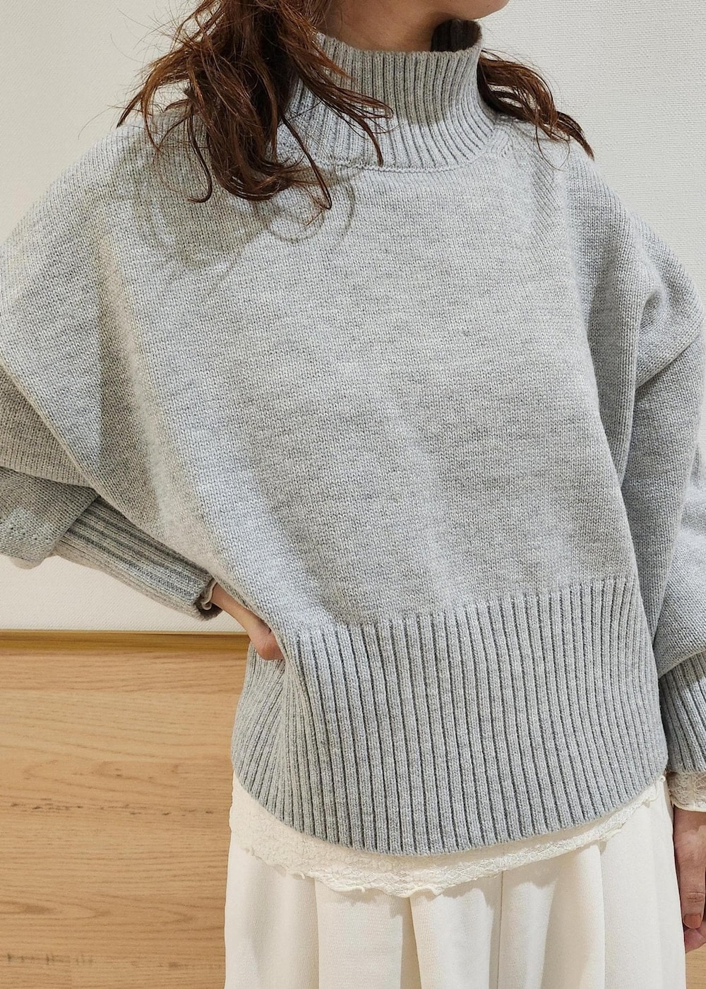 グレー系のニット/セーター、ブラック系のショルダーバッグ、ホワイト系のTシャツ/カットソーを着用したレディースの秋コーディネートの2枚目の写真