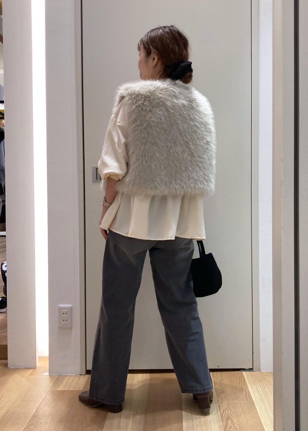 ベージュ系のシャツ/ブラウス、ベージュ系のベスト、ブラック系のデニムパンツを着用したレディースの秋コーディネートの3枚目の写真