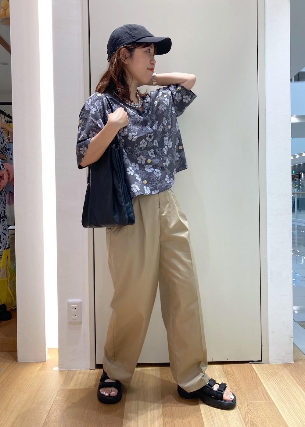 ブラック系のトートバッグ、ブラック系のサンダル、グレー系のチノパンツを着用したレディースの夏コーディネートの2枚目の写真