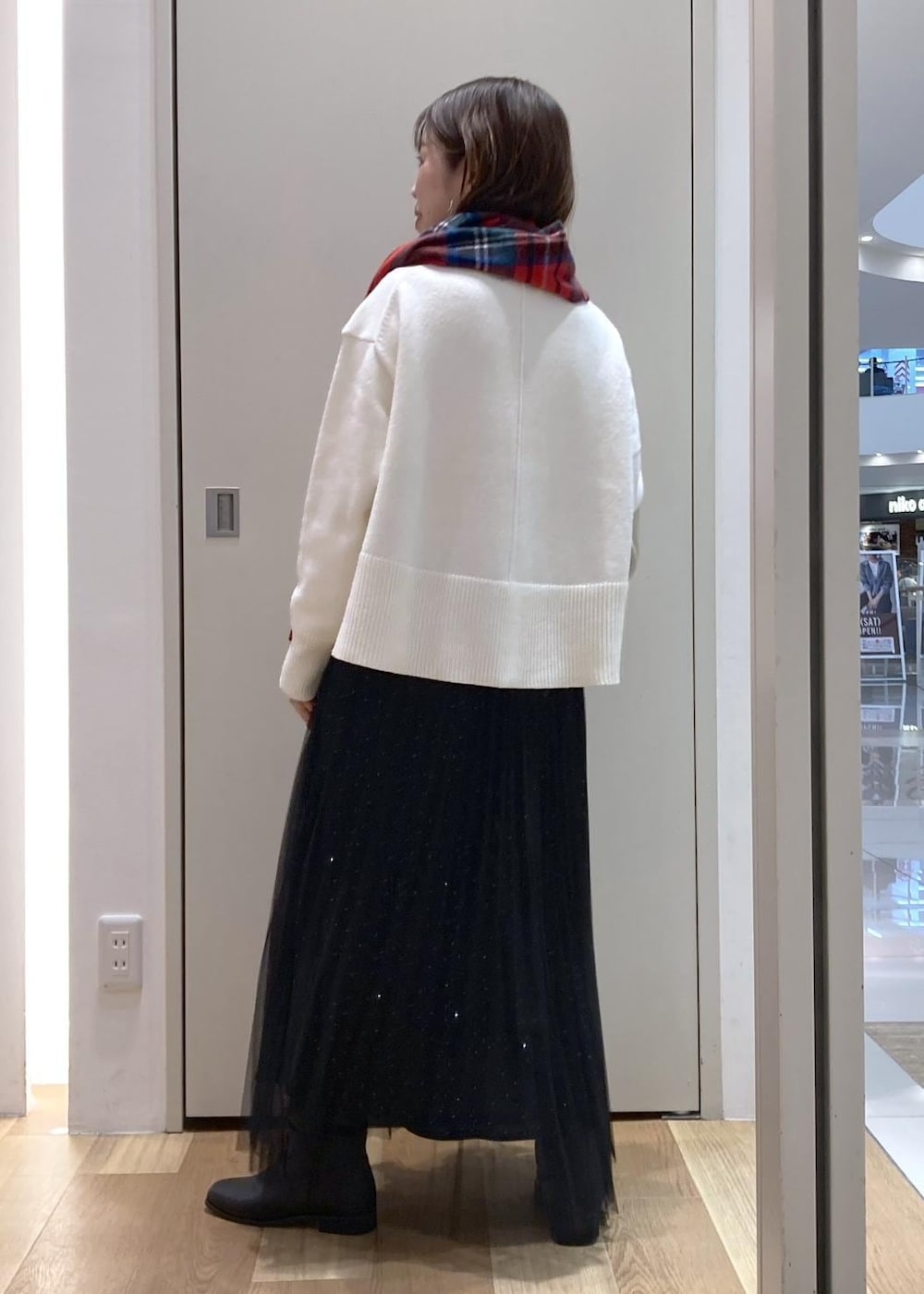 ブラック系のスカート、ホワイト系のニット/セーター、ブラック系のブーツを着用したレディースの冬コーディネートの3枚目の写真