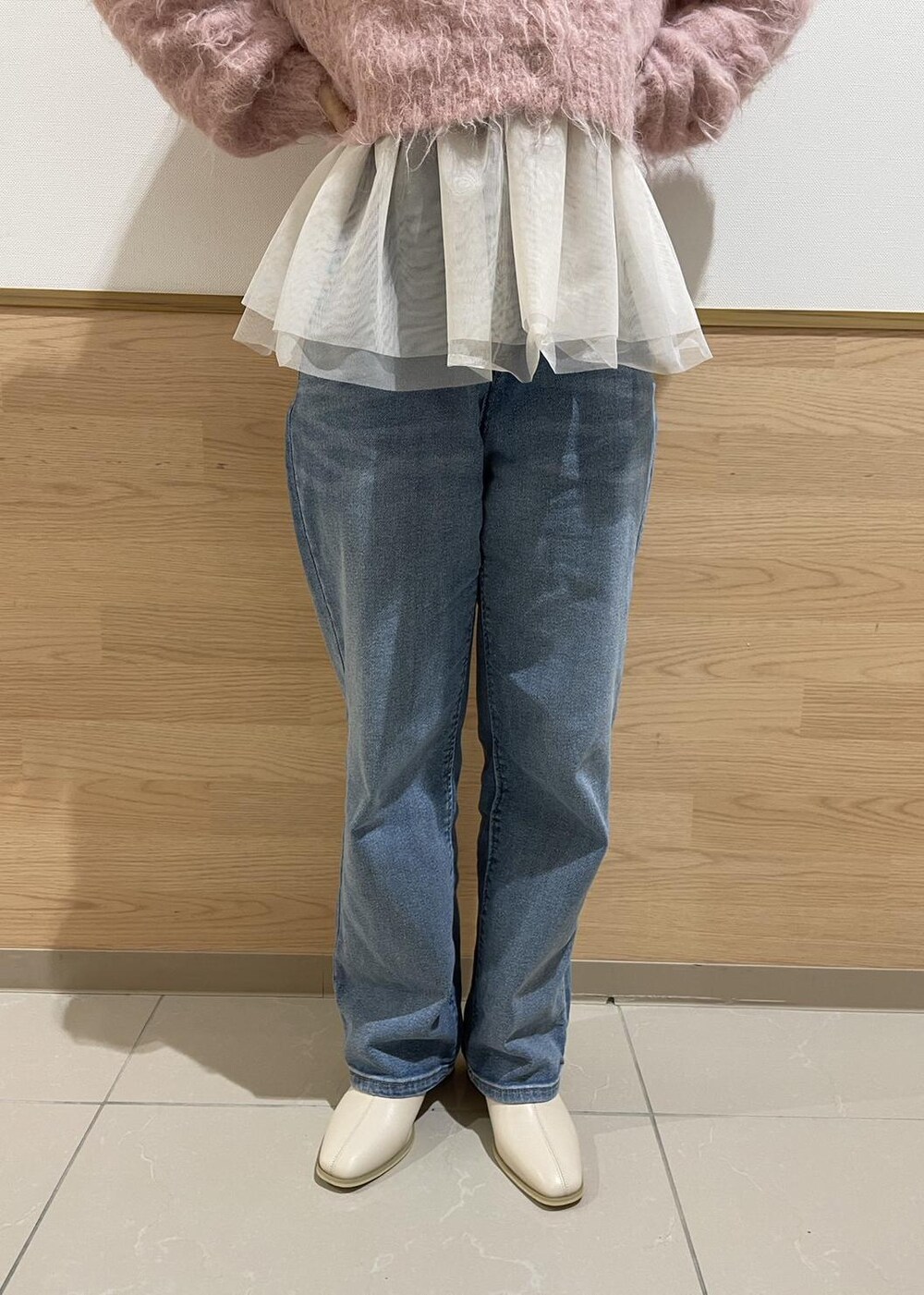 ホワイト系のブーツ、ホワイト系のトートバッグ、ブルー系のデニムパンツを着用したレディースの冬コーディネートの5枚目の写真