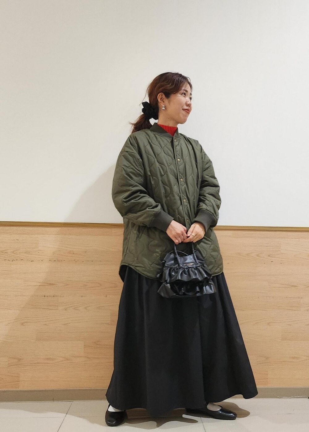 ブラック系のショルダーバッグ、レッド系のニット/セーター、ブラック系のスカートを着用したレディースの秋コーディネートの2枚目の写真