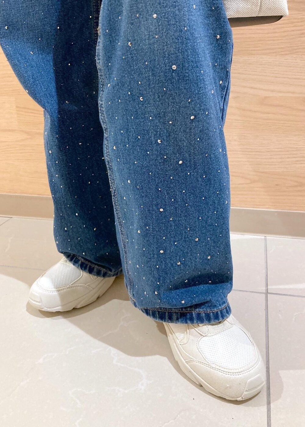 ブルー系のデニムパンツ、ブラック系のトートバッグ、ホワイト系のTシャツ/カットソーを着用したレディースの春コーディネートの7枚目の写真