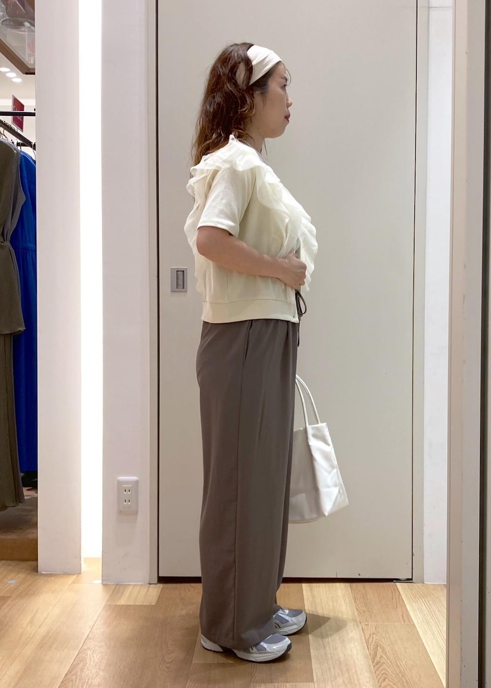 ホワイト系のトートバッグ、ホワイト系のニット/セーター、ベージュ系のTシャツ/カットソーを着用したレディースの夏コーディネートの2枚目の写真