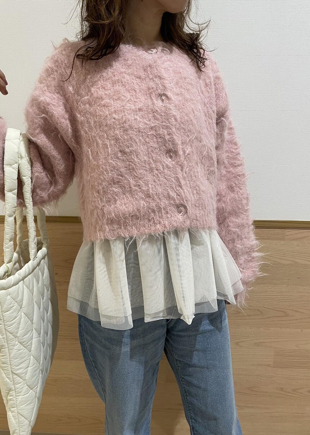 ホワイト系のブーツ、ホワイト系のトートバッグ、ブルー系のデニムパンツを着用したレディースの冬コーディネートの3枚目の写真