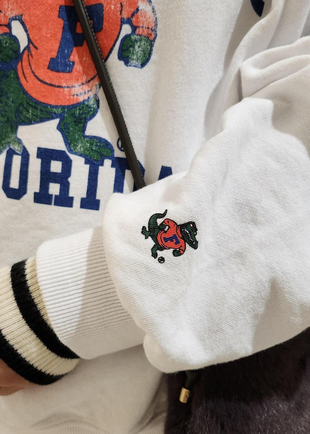 ホワイト系のジャンパースカート、ホワイト系のニット/セーター、グレー系のショルダーバッグを着用したレディースの秋コーディネートの3枚目の写真