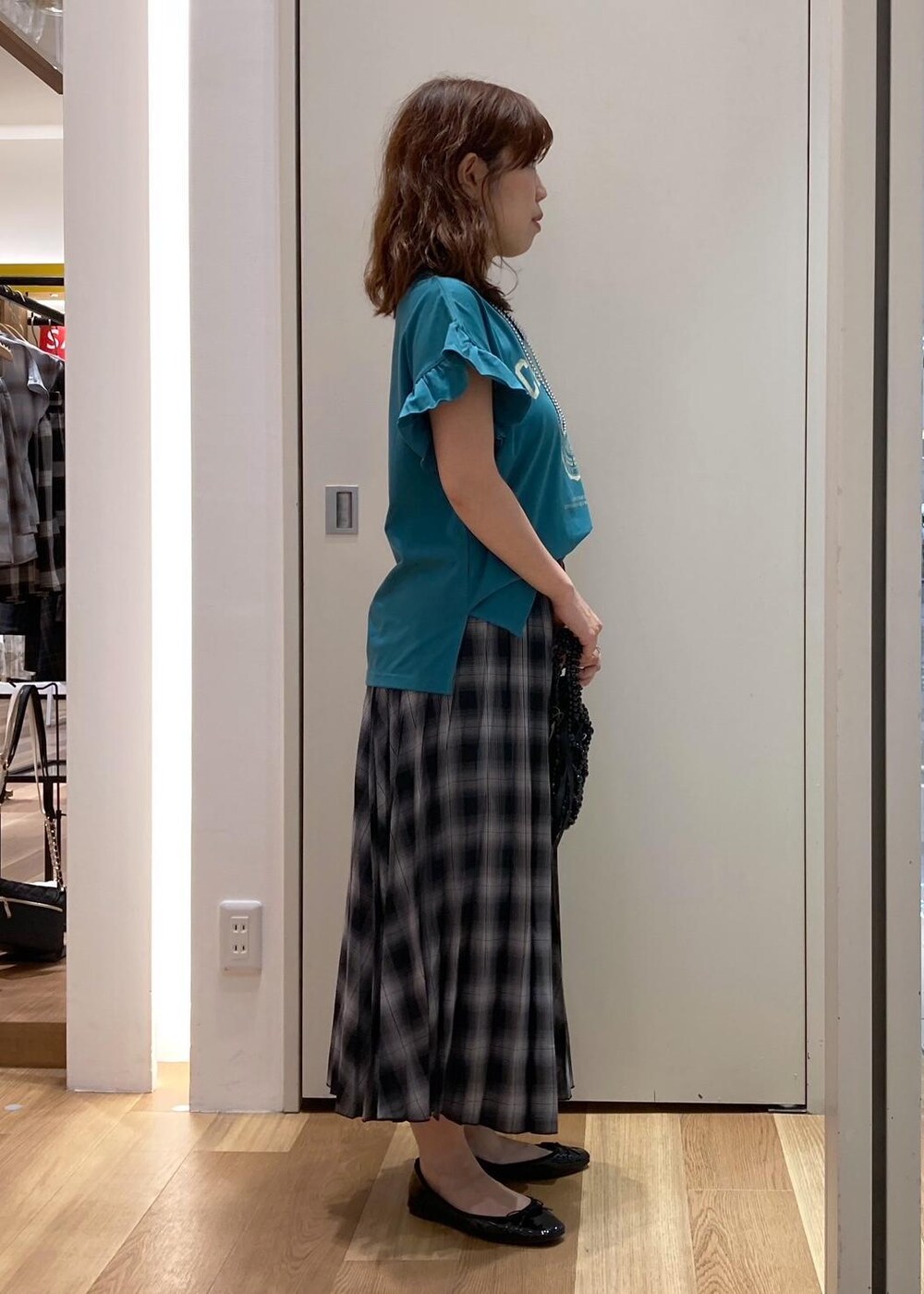 ブラック系のハンドバッグ、ブラック系のバレエシューズ、グリーン系のTシャツ/カットソーを着用したレディースの夏コーディネートの2枚目の写真