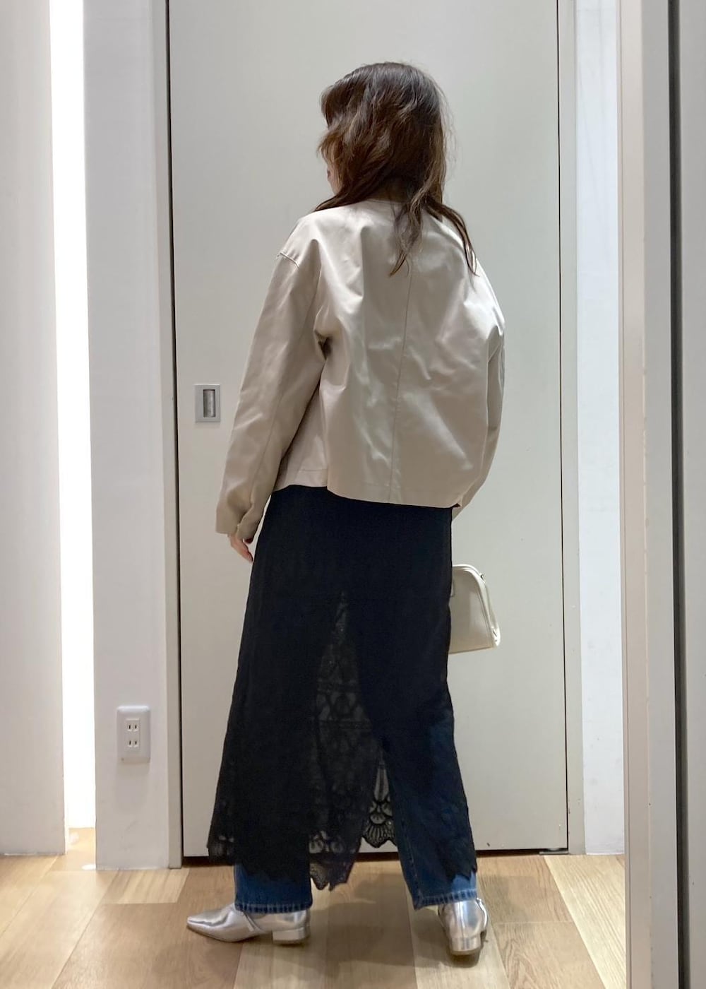 ホワイト系のボストンバッグ、ブルー系のデニムパンツ、ブラック系のワンピースを着用したレディースの春コーディネートの3枚目の写真