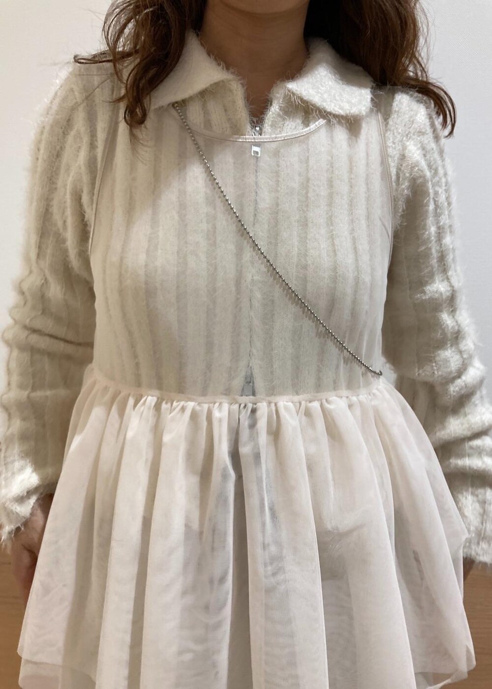 レッド系のショルダーバッグ、ホワイト系のブーツ、ホワイト系のベストを着用したレディースの冬コーディネートの3枚目の写真