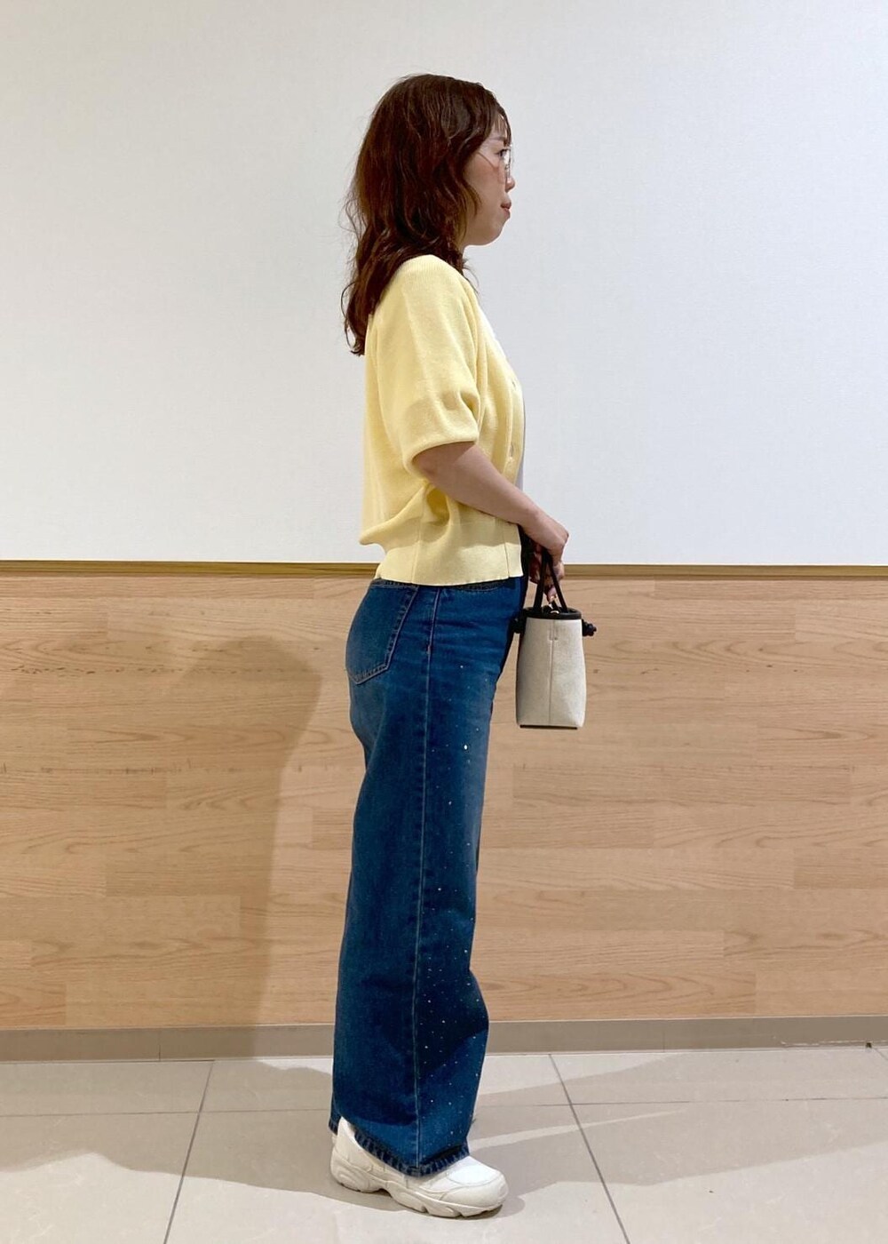 ブルー系のデニムパンツ、ブラック系のトートバッグ、ホワイト系のTシャツ/カットソーを着用したレディースの春コーディネートの3枚目の写真