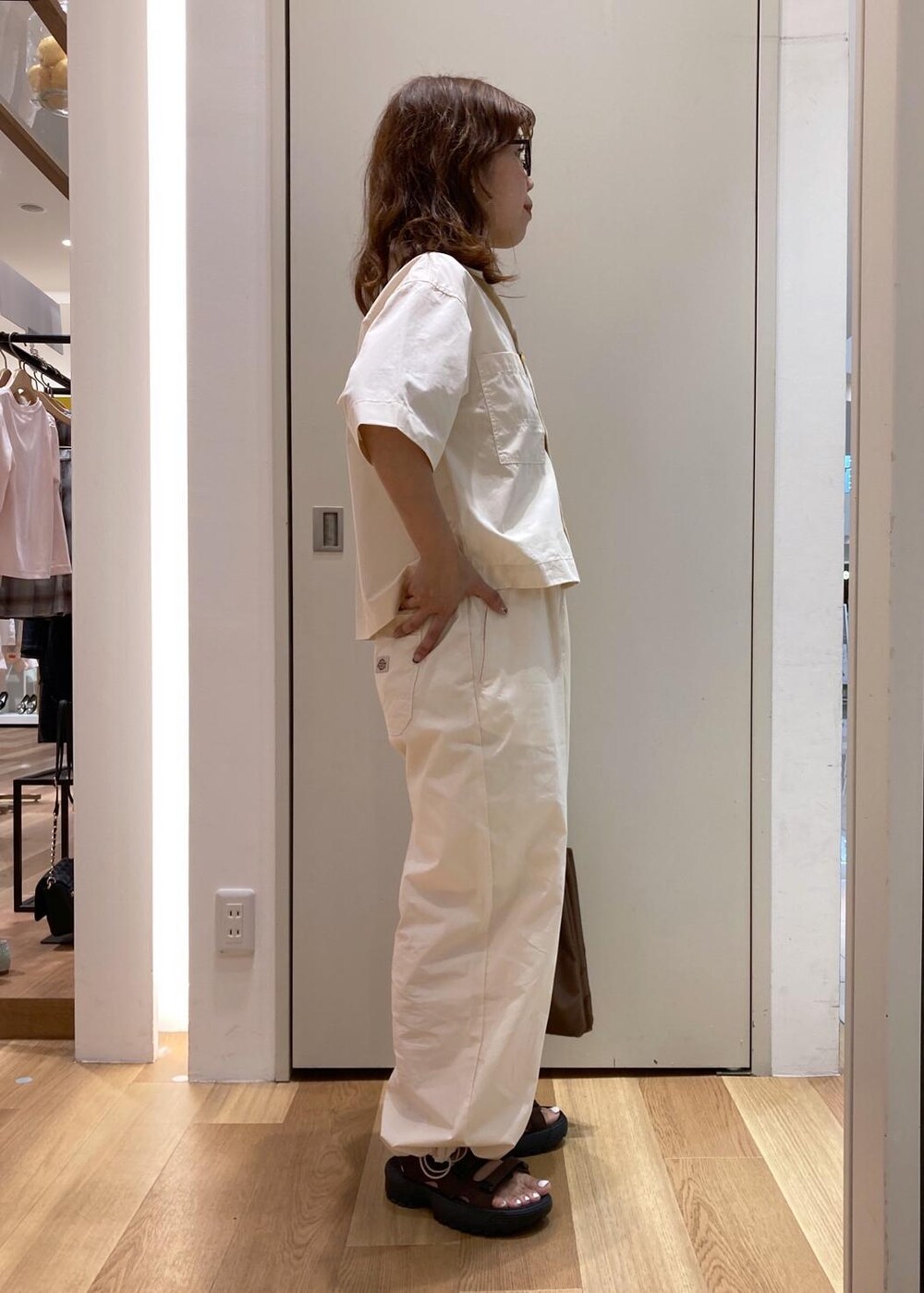 ブラウン系のトートバッグ、ブラウン系のサンダル、ホワイト系のシャツ/ブラウスを着用したレディースの夏コーディネートの3枚目の写真