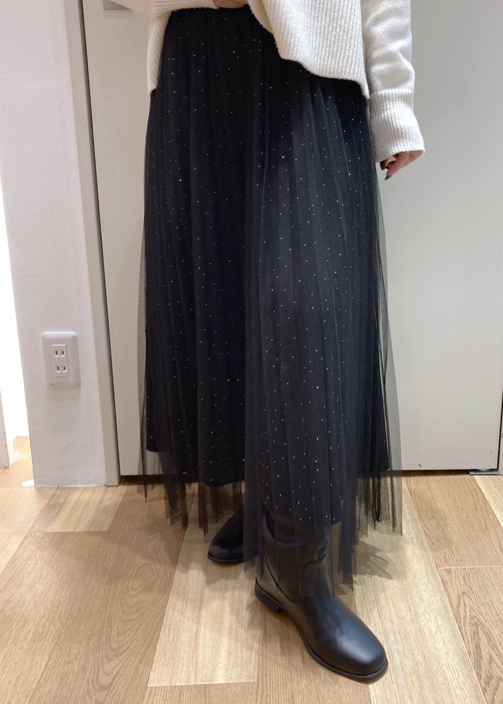 ブラック系のスカート、ホワイト系のニット/セーター、ブラック系のブーツを着用したレディースの冬コーディネートの6枚目の写真