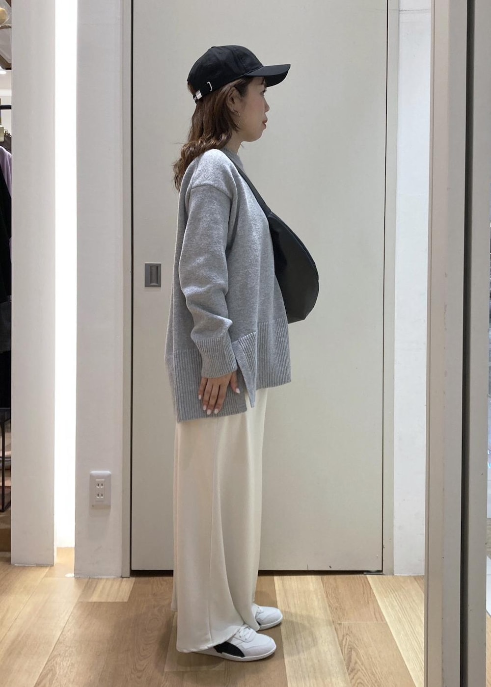 グレー系のニット/セーター、ホワイト系のスニーカー、ブラック系のショルダーバッグを着用したレディースの冬コーディネートの2枚目の写真