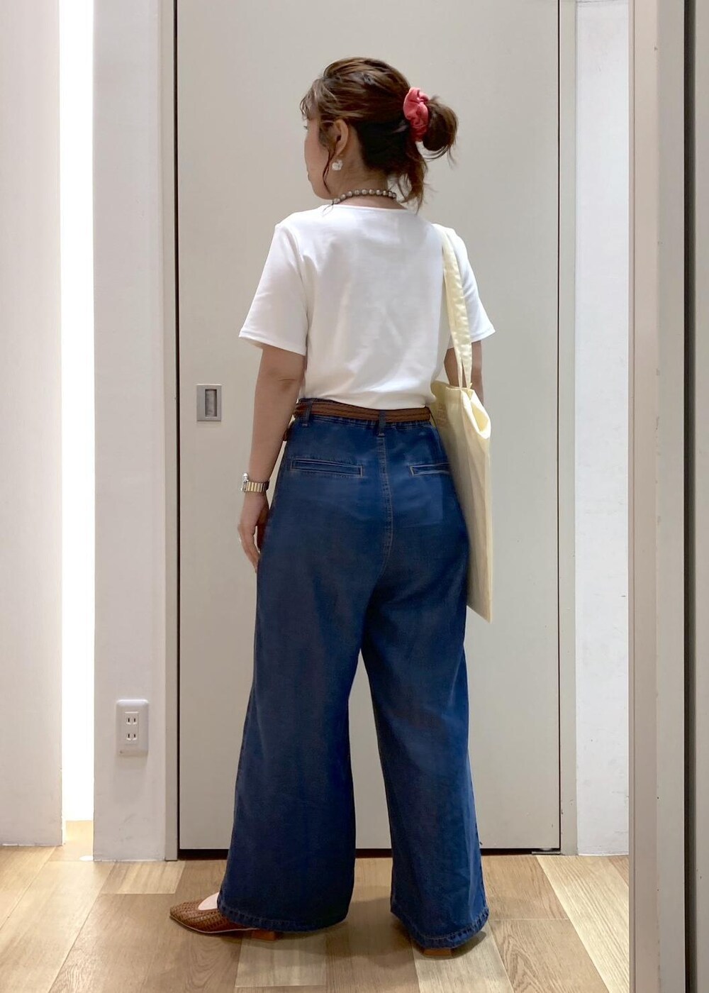 ブラウン系のパンプス、イエロー系のトートバッグ、ブルー系のデニムパンツを着用したレディースの夏コーディネートの3枚目の写真