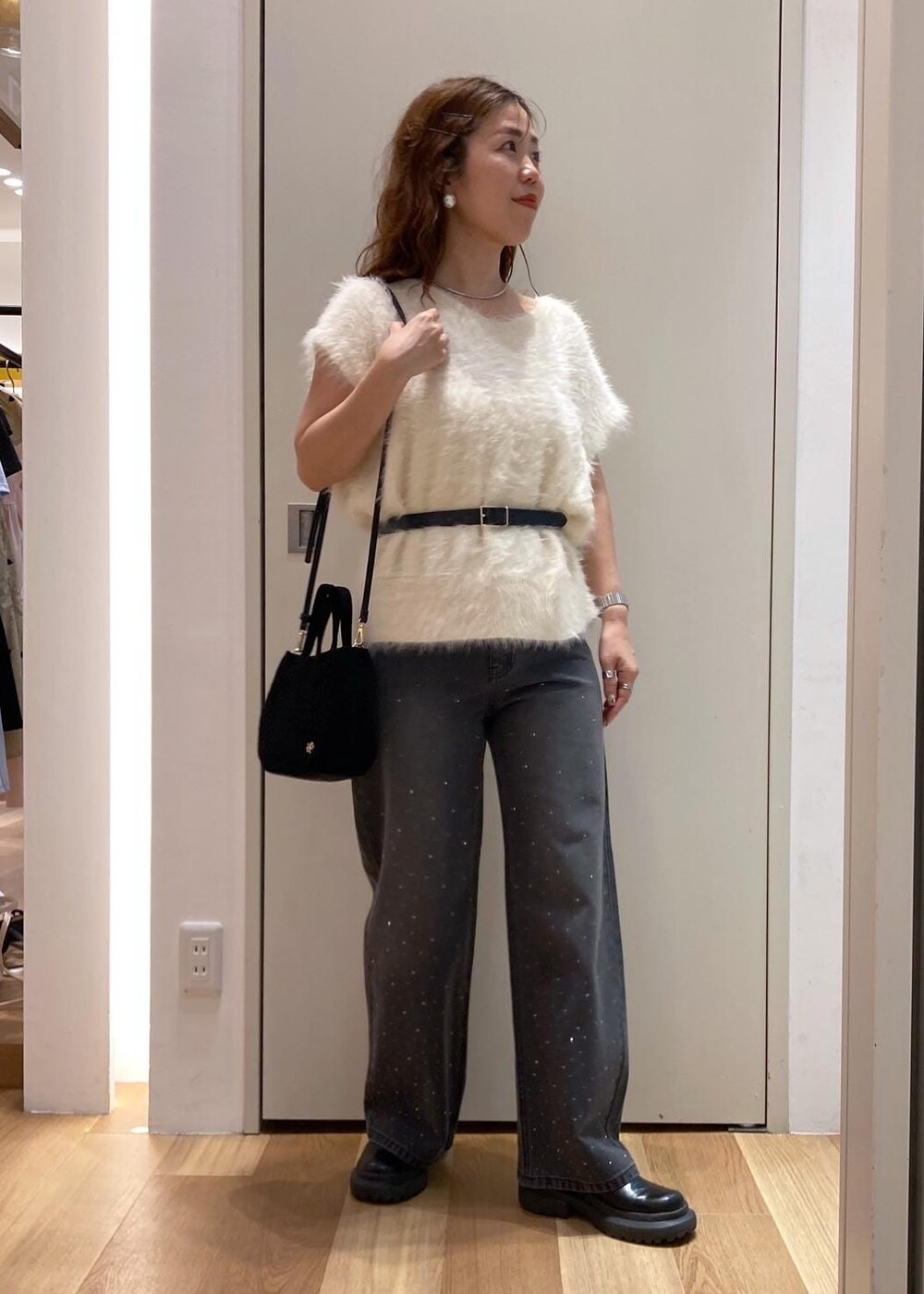 ホワイト系のベスト、ブラック系のデニムパンツ、ブラック系のショルダーバッグを着用したレディースの夏コーディネートの2枚目の写真