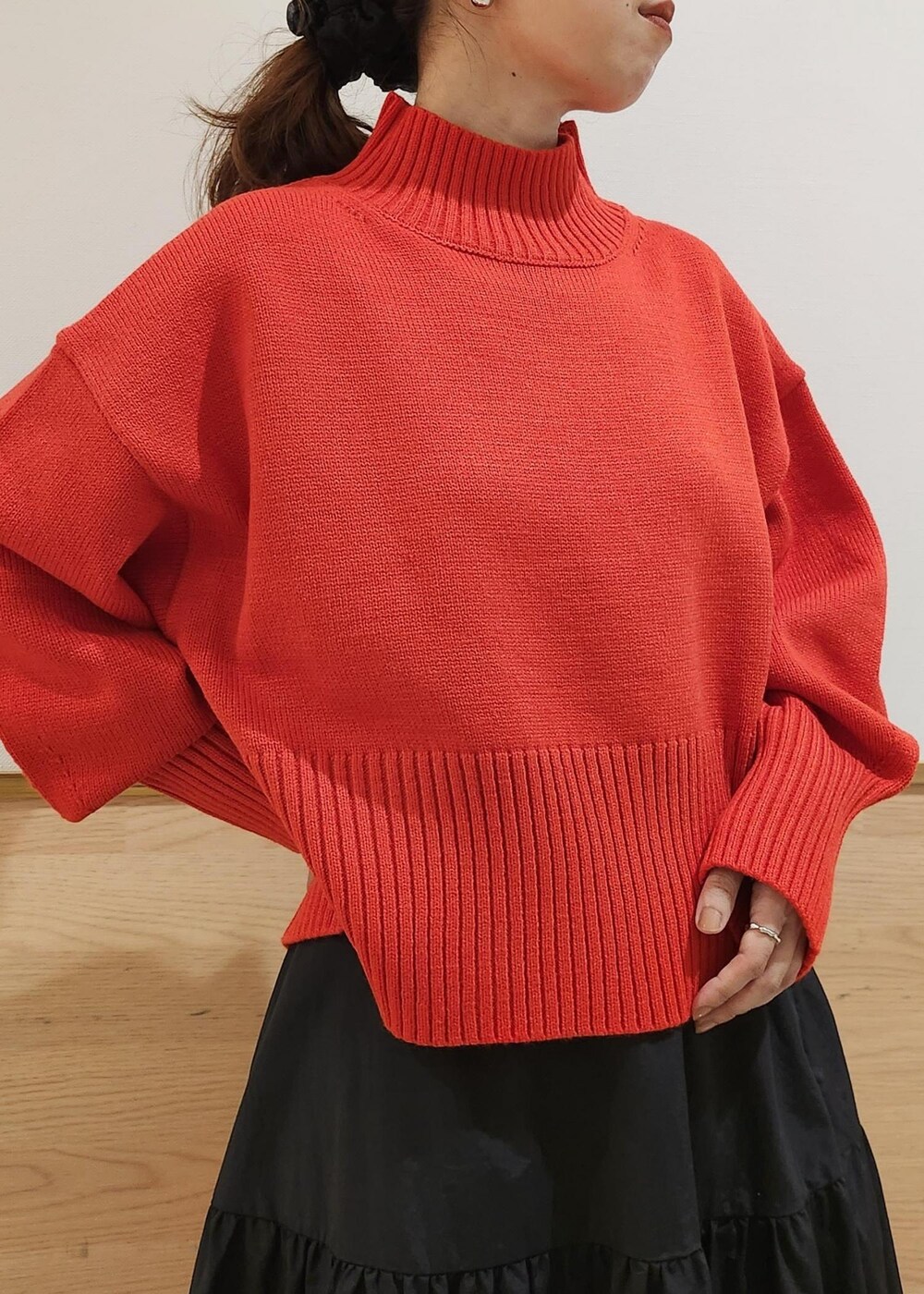 ブラック系のショルダーバッグ、レッド系のニット/セーター、ブラック系のスカートを着用したレディースの秋コーディネートの5枚目の写真