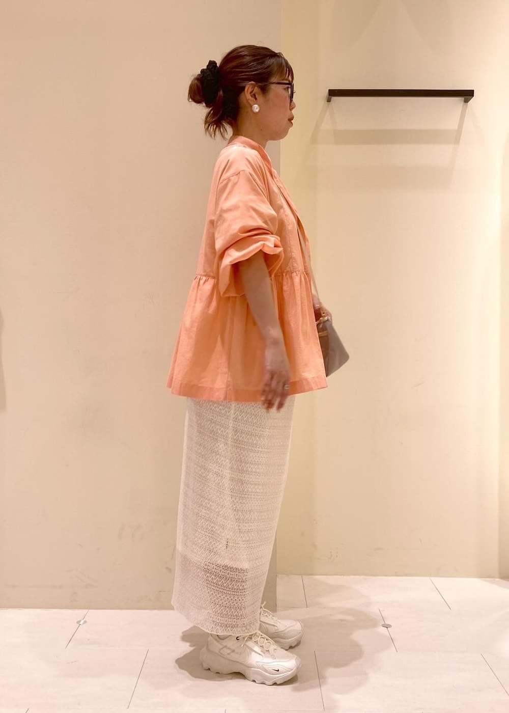 オレンジ系のシャツ/ブラウス、ベージュ系のショルダーバッグ、ホワイト系のTシャツ/カットソーを着用したレディースの春コーディネートの2枚目の写真