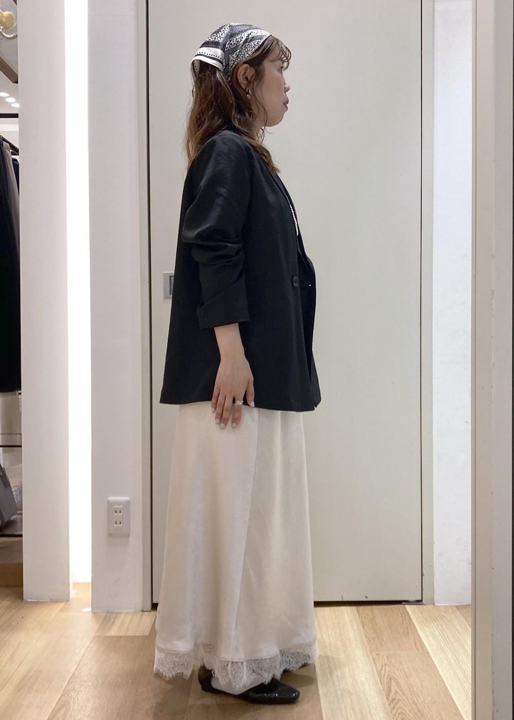 ブラック系のパンプス、ベージュ系のショルダーバッグ、ホワイト系のスカートを着用したレディースの春コーディネートの2枚目の写真