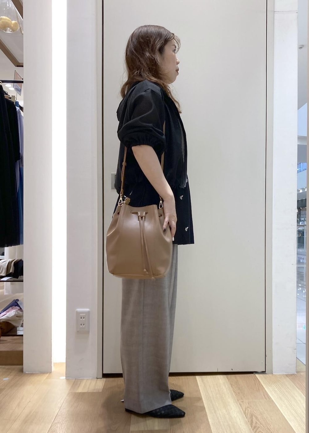 ベージュ系のスラックス、ブラウン系のショルダーバッグ、ブラック系のサンダルを着用したレディースの春コーディネートの2枚目の写真